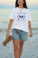 Woman wearing Cape Cod Pickleball Club comfort colors t-shirt on a beach – preppy coastal pickleball apparel for summer and sporty lifestyles.