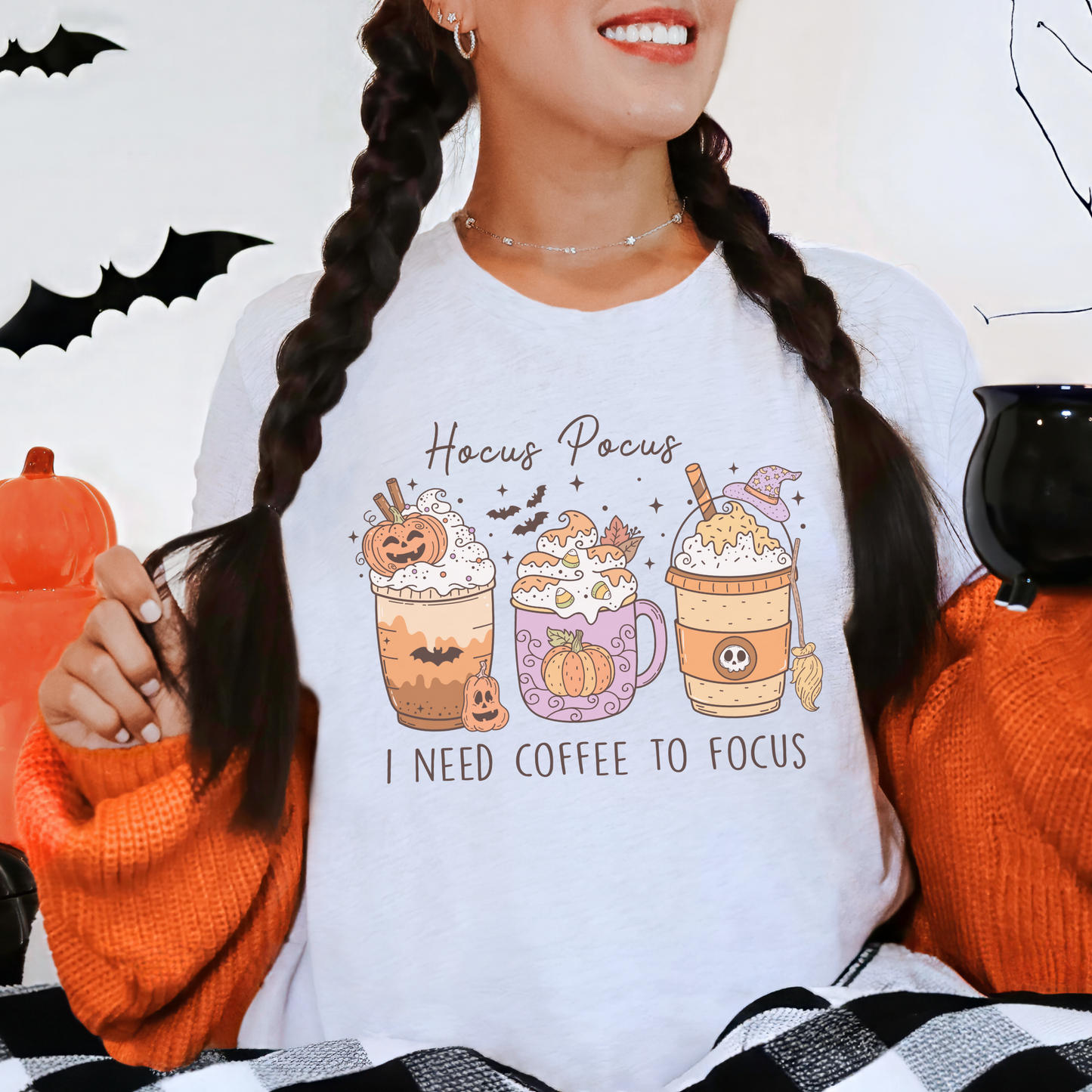 A Bella+Canvas 3001 Tshirt with a Halloween graphic featuring 3 spooky themed coffee drinks. The graphic reads "Hocus pocus I need coffee to focus"