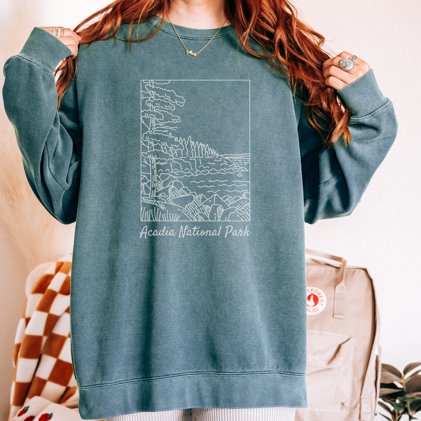 Comfort Colors 1566 Crewneck Sweatshirt with a white illustration graphic of a scene from Acadia National Park. The graphic reads "Acadia National Park" under the image.