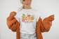 Bella Canvas 3001 Tshirt with a western halloween scene of jack o lanterns wearing western gear in the desert. The graphic reads I teach the wildest pumpkins.