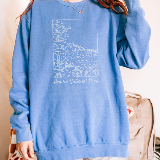 Comfort Colors 1566 Crewneck Sweatshirt with a white illustration graphic of a scene from Acadia National Park. The graphic reads "Acadia National Park" under the image.