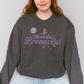 Crewneck sweatshirt with a simple witch and full moon graphic and retro inspired font that reads Moons out Brooms out in purple.