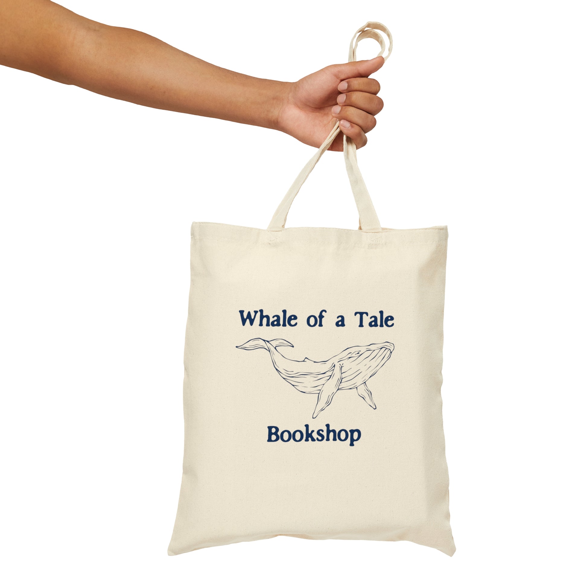 A canvas tote bag with a navy blue DTG graphic that features a whale and reads "Whale of a Tale Bookshop"