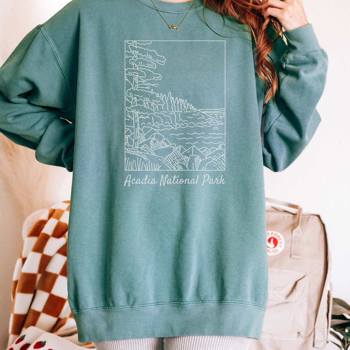 Comfort Colors 1566 Crewneck Sweatshirt with a white illustration graphic of a scene from Acadia National Park. The graphic reads "Acadia National Park" under the image.