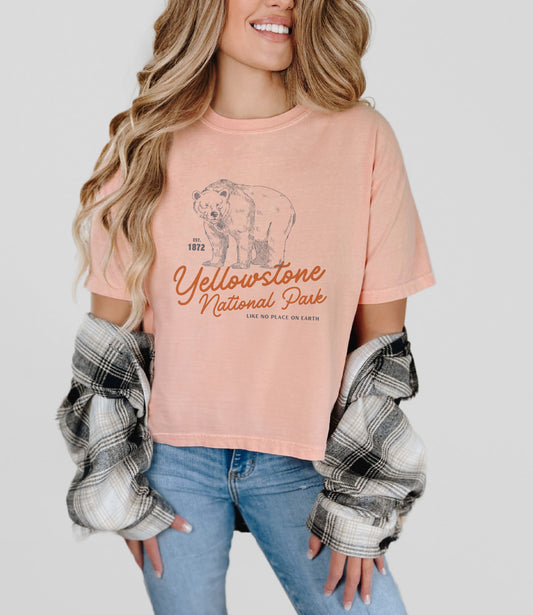 Model wearing peach-colored cropped Comfort Colors tee with Yellowstone bear graphic and “Like No Place On Earth” slogan – outdoorsy granola girl aesthetic