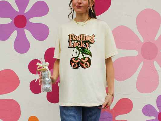 Model wearing Retro graphic t-shirt with “Feeling Lucky” text and cherry stems featuring pink 8-balls, printed on a Comfort Colors tee.