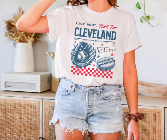 White Comfort Colors Tshirt with a Vintage Inspired baseball graphic. The graphic features a baseball glove, ball, and hotdog and various sports items. The text reads Root, Root, Root for Cleveland!